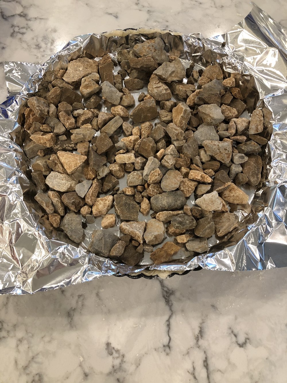 Blind bake the pie crust while you prepare the lemon filling. Blind Bake simply means to bake the crust first with no filling. Use pie weights (or in my case clean rocks b/c I didn’t have any weights) to hold down the crust from puffing up while baking.