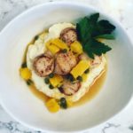 five Sea Scallops over top mashed cauliflower with orange segments and capers. garnished with parsley.