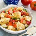 Round bowl full to the top with TORTELLINI PASTA, tomatoes, cucumbers and feta cheese.