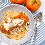 Pomodoro Sauce over grilled chicken that's on top of the angel hair pasta. Parm cheese is sprinkled on top.