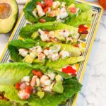 SHRIMP-CEVICHE loaded in to romaine LETTUCE-BOATS. Lettuce boats are lined up on a colorful rectangle platter.