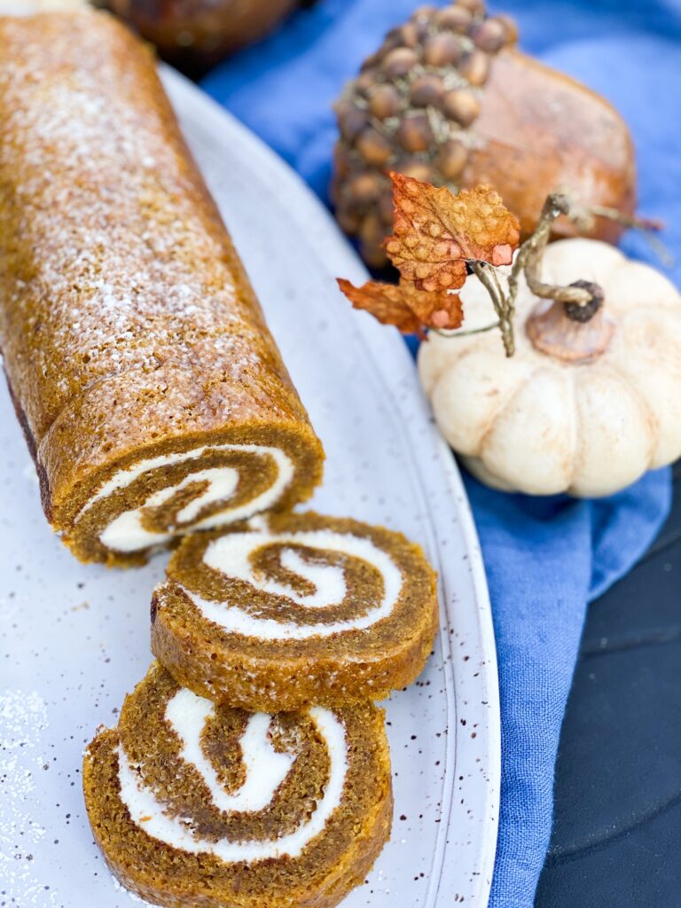 Grandmothers Pumpkin Roll on a gray platter with 2 slices cut and displayed 