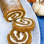 Grandmothers Pumpkin Roll on a gray platter with 2 slices cut and displayed