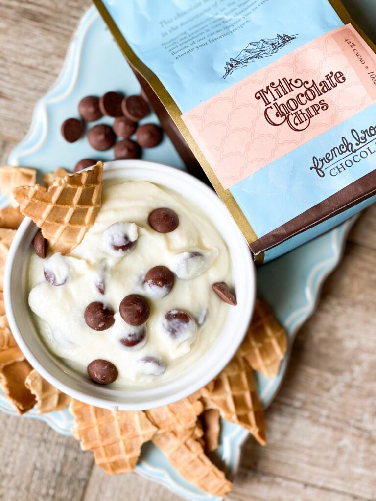 CANNOLI DIP in a white bowl sitting on a light blue tray and waffle cone pieces for dipping