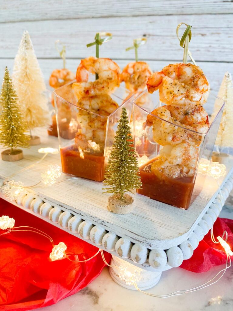 Three cooked shrimp on a tooth pick in little individual cups