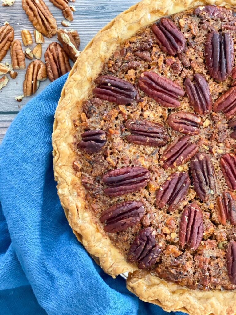 Pecan Pie in a pie plate sitting on a blue towel 