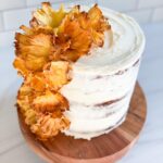 hummingbird cake with white icing and yellow flowers made from dried pineapples