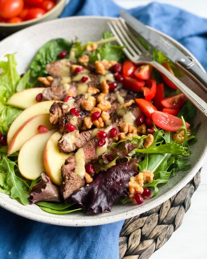STEAK SALAD in a large bowl with apple slices and pomegranate seeds