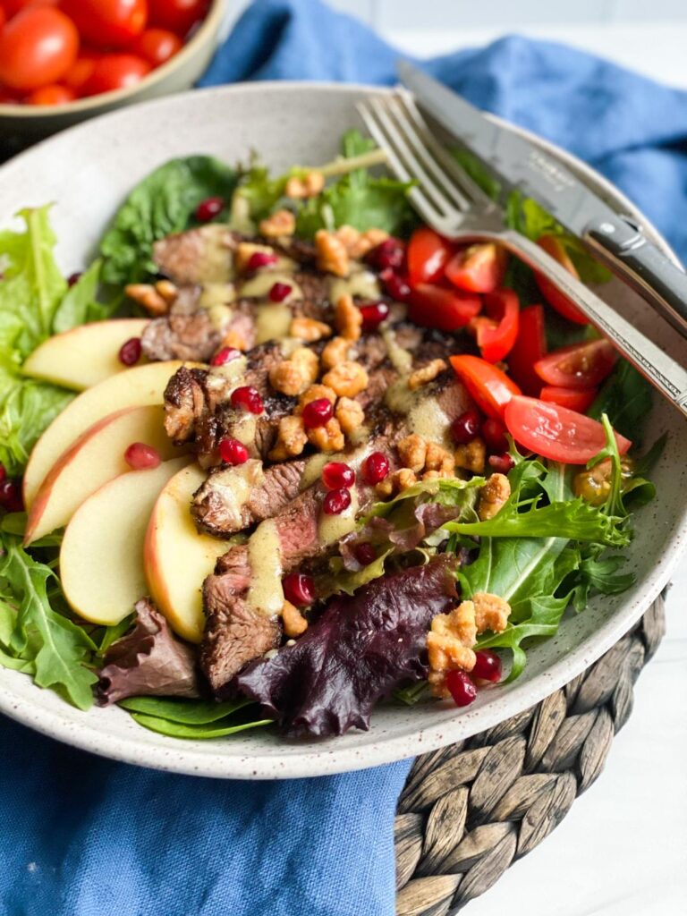STEAK SALAD in a large bowl with apple slices and pomegranate seeds