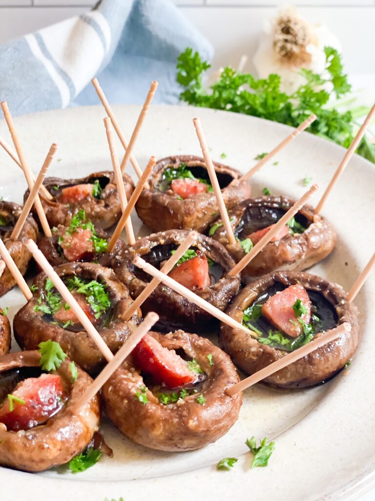 Mushroom caps with a piece of sausage in the middle. Each mushroom has two toothpicks