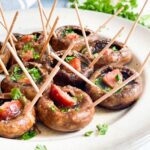 Mushroom caps with a piece of sausage in the middle. Each mushroom has two toothpicks